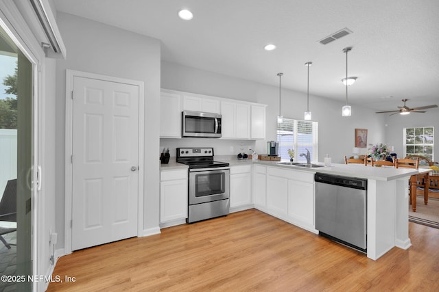 724 N Pine Ave, Green Cove Springs, FL 32043 - kitchen featuring appliances with stainless steel finishes, light wood-type flooring, a peninsula, white cabinetry, and light countertops