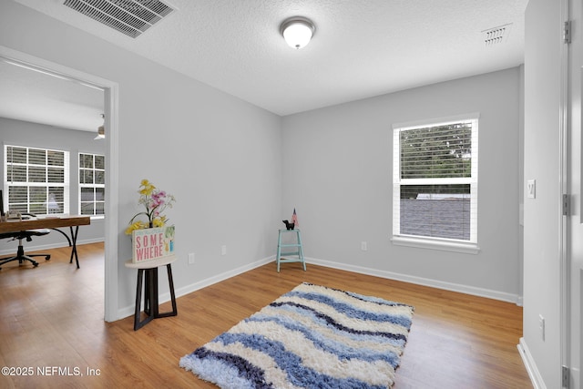 724 N Pine Ave, Green Cove Springs, FL 32043 - bedroom featuring wood finished floors, multiple windows, a textured ceiling, and an office area