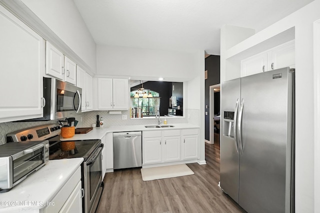14410 Pelican Bay Ct, Jacksonville, FL 32224 - kitchen featuring appliances with stainless steel finishes, tasteful backsplash, white cabinets, light wood-type flooring, and light countertops