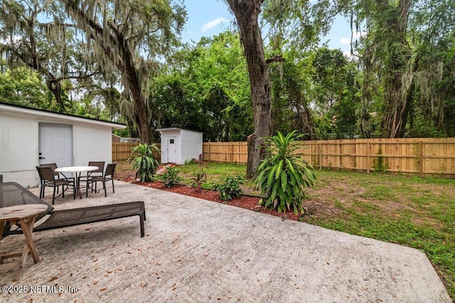 2571 Montreal St, Jacksonville, FL 32233 - fenced backyard featuring a patio, a storage unit, outdoor dining area, and view of wooded area