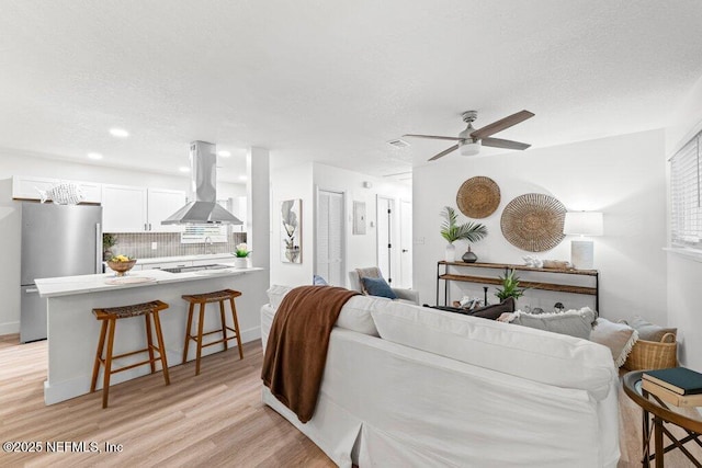 2571 Montreal St, Jacksonville, FL 32233 - living room with light wood-style flooring, a ceiling fan, and a textured ceiling