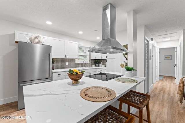 2571 Montreal St, Jacksonville, FL 32233 - kitchen featuring island exhaust hood, freestanding refrigerator, black electric stovetop, a kitchen breakfast bar, and a textured ceiling