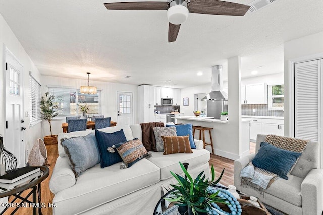2571 Montreal St, Jacksonville, FL 32233 - living area featuring light wood finished floors, a chandelier, plenty of natural light, ceiling fan, and a textured ceiling