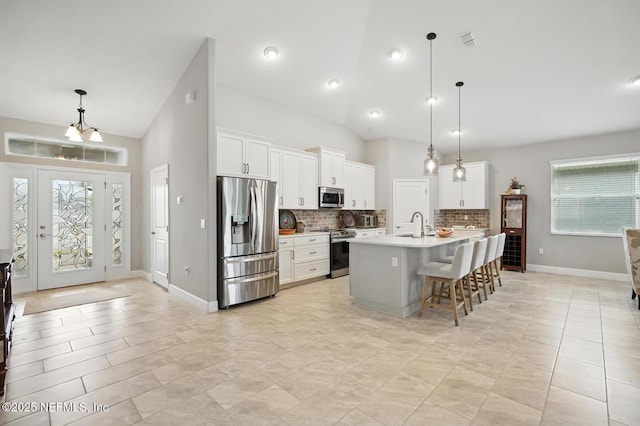 29 Lagoon Way, Palm Coast, FL 32137 - kitchen with stainless steel appliances, decorative backsplash, a breakfast bar area, light countertops, and white cabinetry