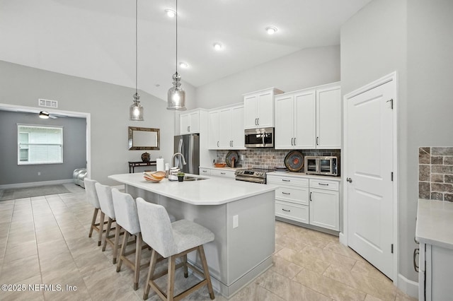 29 Lagoon Way, Palm Coast, FL 32137 - kitchen with appliances with stainless steel finishes, lofted ceiling, backsplash, a breakfast bar, and a center island with sink