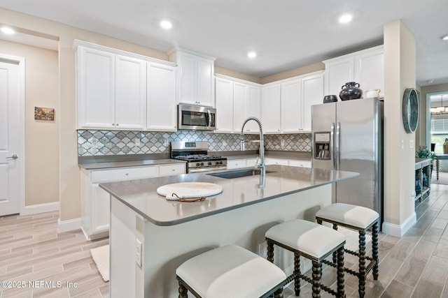 3146 Villa Vera Ct, Jacksonville, FL 32246 - kitchen with appliances with stainless steel finishes, wood tiled floors, tasteful backsplash, a breakfast bar, and white cabinetry