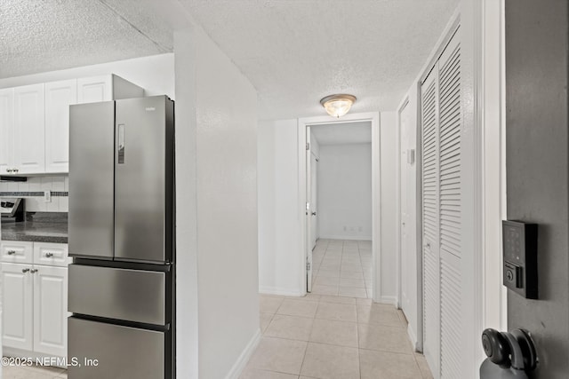 355 Monument Rd Unit 15D1, Jacksonville, FL 32225 - kitchen featuring freestanding refrigerator, a textured ceiling, dark countertops, light tile patterned flooring, and white cabinets