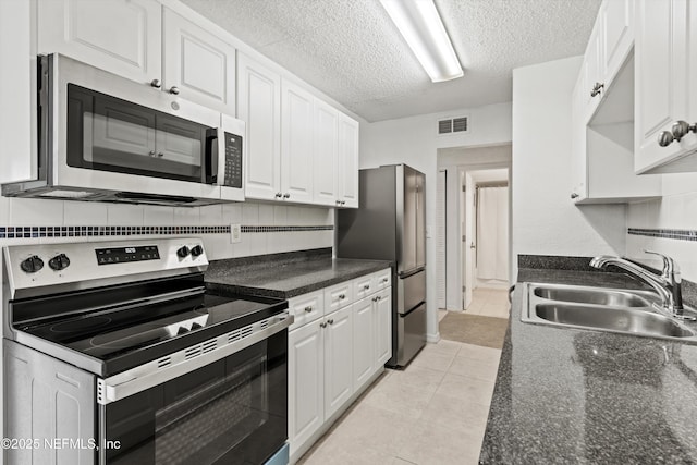 355 Monument Rd Unit 15D1, Jacksonville, FL 32225 - kitchen featuring appliances with stainless steel finishes, white cabinets, light tile patterned floors, dark countertops, and a textured ceiling