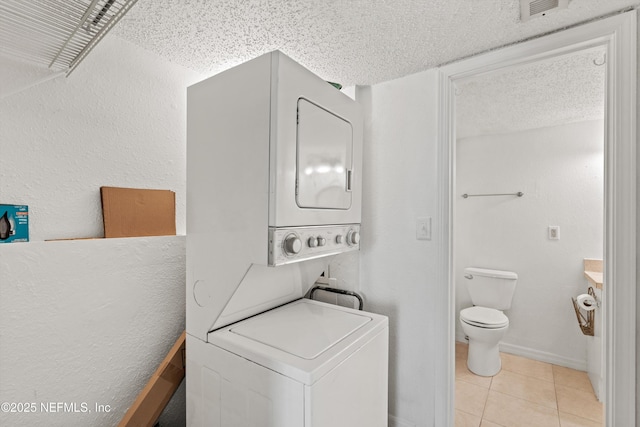 355 Monument Rd Unit 15D1, Jacksonville, FL 32225 - washroom featuring stacked washing machine and dryer, tile patterned flooring, and a textured ceiling