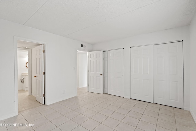 355 Monument Rd Unit 15D1, Jacksonville, FL 32225 - unfurnished bedroom with two closets, light tile patterned flooring, a textured ceiling, and ensuite bath