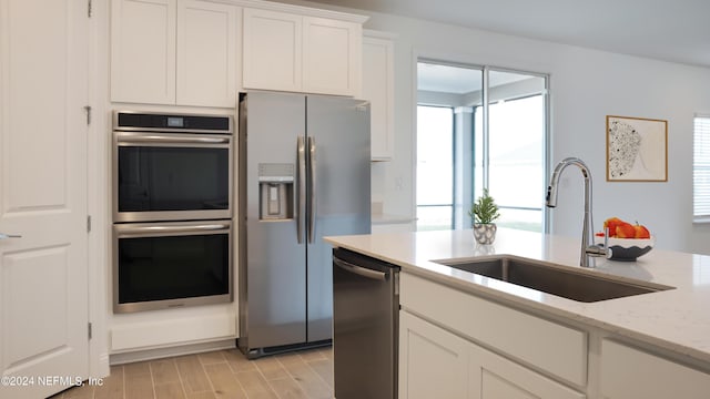 324 Higgins Loop, Saint Augustine, FL 32092 - kitchen with stainless steel appliances, white cabinetry, light stone countertops, and light wood-type flooring
