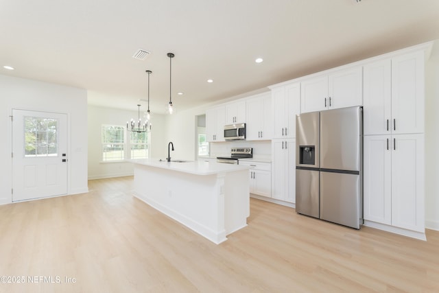 1861 Openwoods Rd, Middleburg, FL 32068 - kitchen with stainless steel appliances, light wood-style flooring, a kitchen island with sink, white cabinets, and recessed lighting
