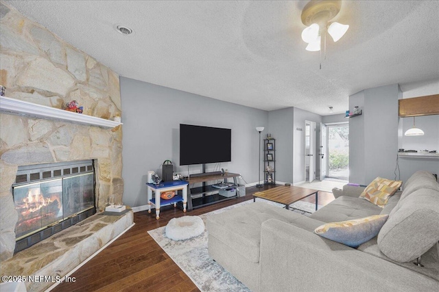 7632 Rain Forest Dr W, Jacksonville, FL 32277 - living room with a textured ceiling, wood finished floors, a ceiling fan, and a fireplace