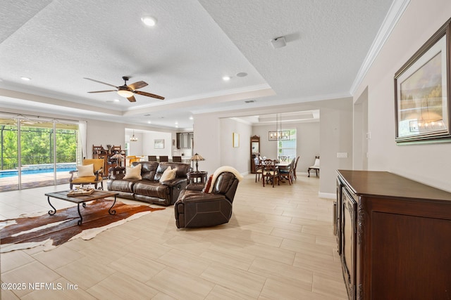 121 Seamount Way, Saint Augustine, FL 32092 - living room featuring a tray ceiling, crown molding, a textured ceiling, a ceiling fan, and plenty of natural light