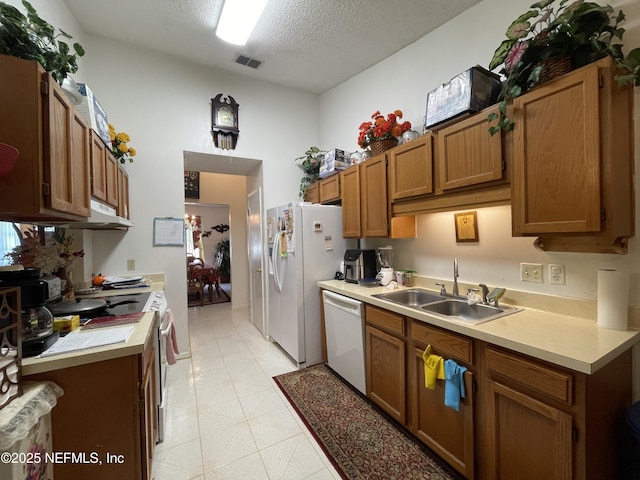 1038 Celebrant Dr, Jacksonville, FL 32225 - kitchen featuring white appliances, brown cabinetry, light countertops, a textured ceiling, and under cabinet range hood