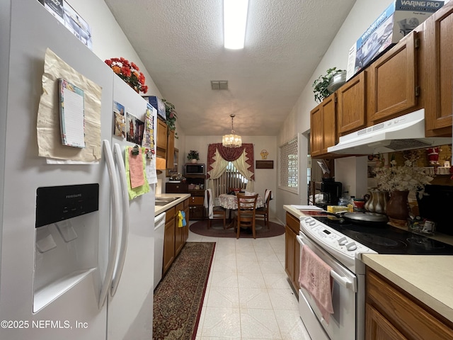 1038 Celebrant Dr, Jacksonville, FL 32225 - kitchen featuring white appliances, under cabinet range hood, brown cabinets, a chandelier, and light countertops