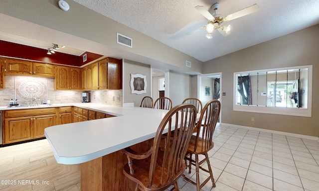 5110 Janice Cir E, Jacksonville, FL 32210 - kitchen with lofted ceiling, backsplash, light countertops, a textured ceiling, and a peninsula