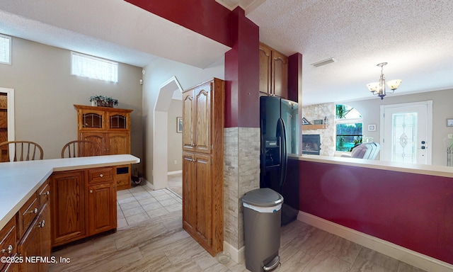 5110 Janice Cir E, Jacksonville, FL 32210 - kitchen with black fridge with ice dispenser, brown cabinets, light countertops, a chandelier, and hanging light fixtures