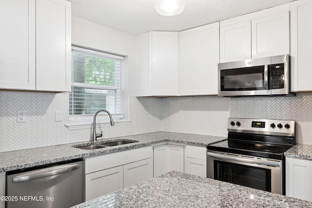 3349 Gilmore St, Jacksonville, FL 32205 - kitchen featuring stainless steel appliances, white cabinets, backsplash, and light stone counters