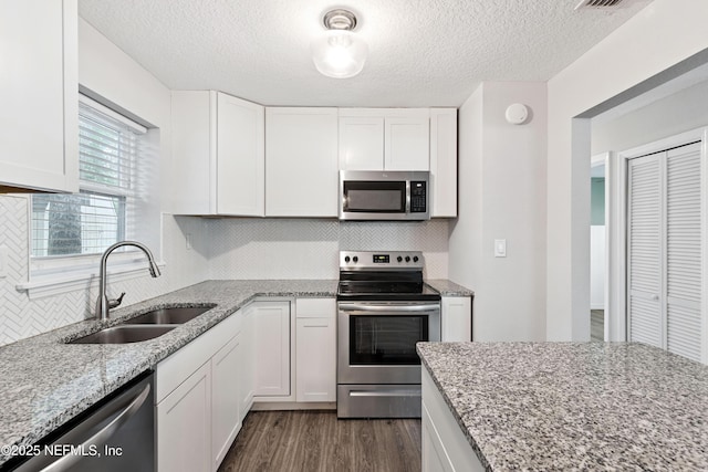 3349 Gilmore St, Jacksonville, FL 32205 - kitchen featuring stainless steel appliances, backsplash, white cabinetry, dark wood finished floors, and light stone countertops