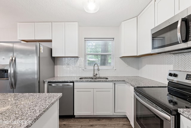 3349 Gilmore St, Jacksonville, FL 32205 - kitchen featuring appliances with stainless steel finishes, white cabinets, dark wood finished floors, light stone counters, and a textured ceiling