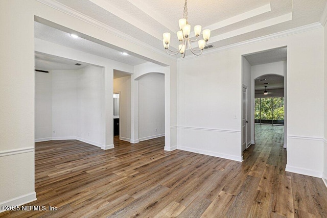 1103 Orchard Oriole Pl, Middleburg, FL 32068 - unfurnished room featuring arched walkways, a chandelier, wood finished floors, ornamental molding, and a tray ceiling