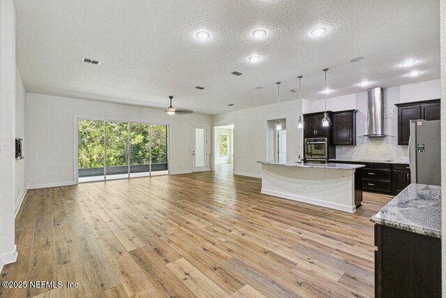 1103 Orchard Oriole Pl, Middleburg, FL 32068 - kitchen featuring open floor plan, wall chimney range hood, freestanding refrigerator, a textured ceiling, and light wood-type flooring