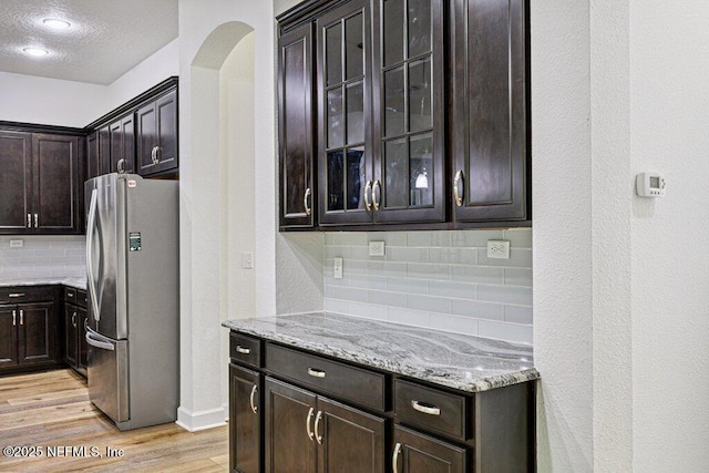 1103 Orchard Oriole Pl, Middleburg, FL 32068 - kitchen with freestanding refrigerator, tasteful backsplash, arched walkways, light stone counters, and a textured ceiling