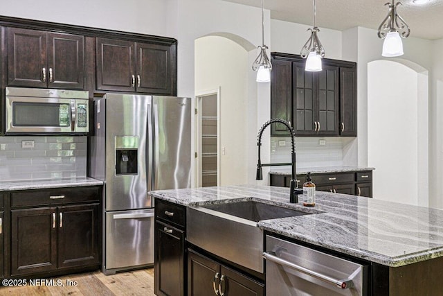 1103 Orchard Oriole Pl, Middleburg, FL 32068 - kitchen featuring stainless steel appliances, arched walkways, backsplash, light stone counters, and hanging light fixtures