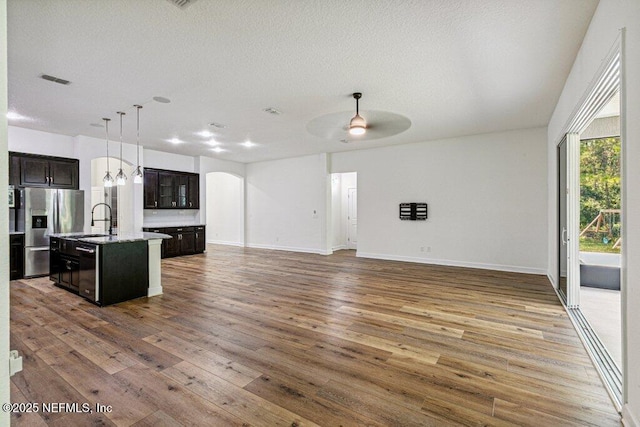 1103 Orchard Oriole Pl, Middleburg, FL 32068 - kitchen featuring stainless steel fridge, open floor plan, an island with sink, hardwood / wood-style flooring, and a textured ceiling