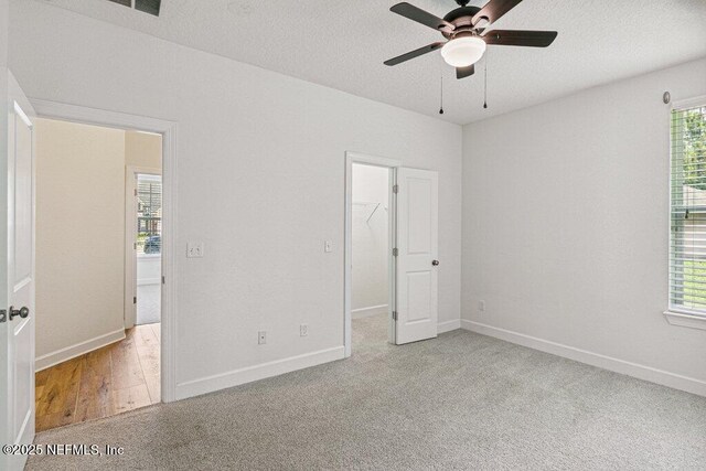 1103 Orchard Oriole Pl, Middleburg, FL 32068 - unfurnished bedroom with a spacious closet, multiple windows, a textured ceiling, and a ceiling fan