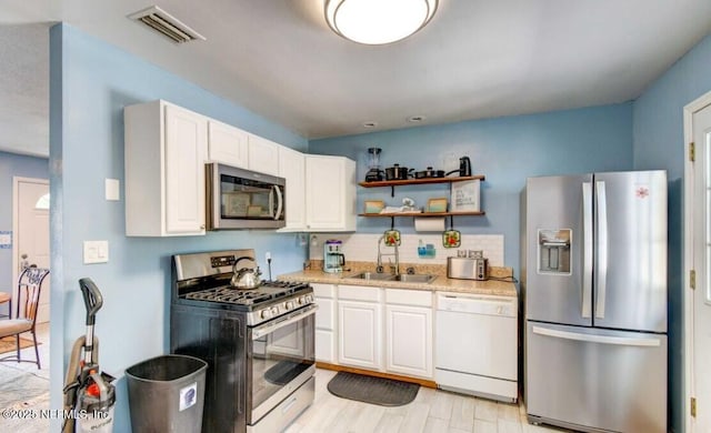 1922 Locust Ave, Palatka, FL 32177 - kitchen with stainless steel appliances, open shelves, light countertops, white cabinets, and tasteful backsplash