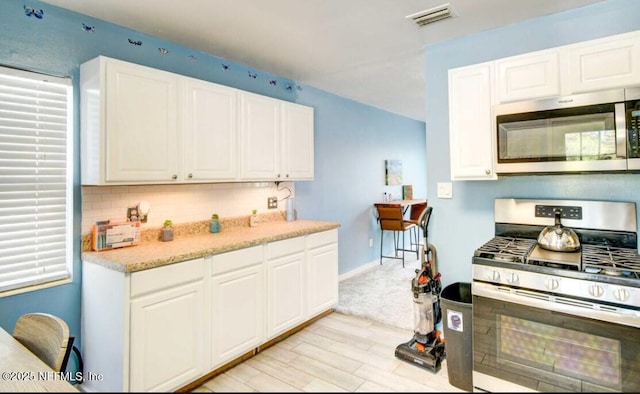 1922 Locust Ave, Palatka, FL 32177 - kitchen featuring stainless steel appliances, light wood-style flooring, decorative backsplash, and white cabinetry