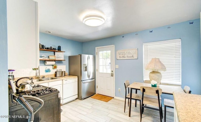 1922 Locust Ave, Palatka, FL 32177 - kitchen with gas stove, white cabinets, light countertops, open shelves, and white dishwasher