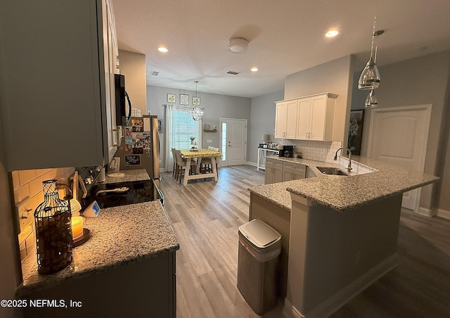 51321 Bloomington Way, Callahan, FL 32011 - kitchen featuring tasteful backsplash, light stone counters, a peninsula, light wood finished floors, and recessed lighting