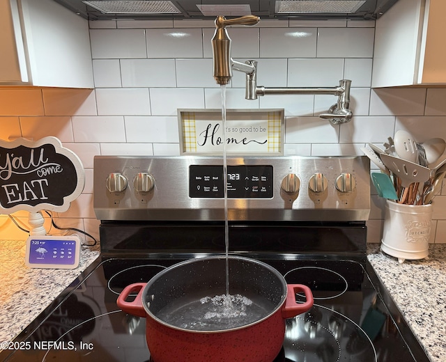 51321 Bloomington Way, Callahan, FL 32011 - kitchen view of tasteful backsplash, stainless steel range with electric stovetop, pot filler, and light stone countertops