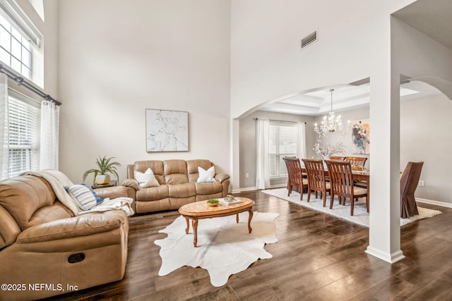 1020 Candlebark Dr, Jacksonville, FL 32225 - living room featuring arched walkways, dark wood-type flooring, a towering ceiling, and a chandelier