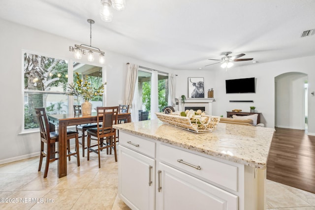 1020 Candlebark Dr, Jacksonville, FL 32225 - kitchen with a ceiling fan, arched walkways, pendant lighting, white cabinets, and light stone counters