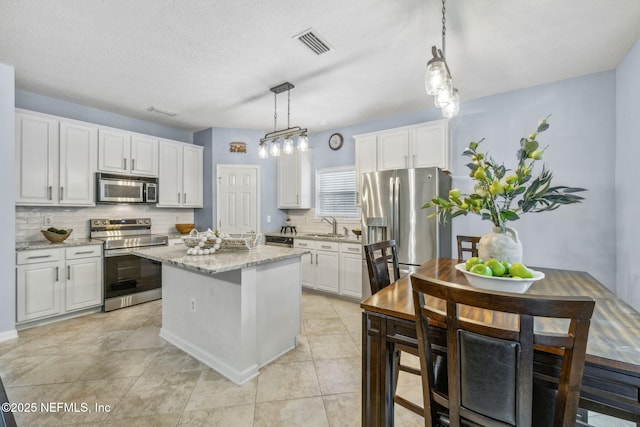 1020 Candlebark Dr, Jacksonville, FL 32225 - kitchen with stainless steel appliances, tasteful backsplash, white cabinetry, and a kitchen island