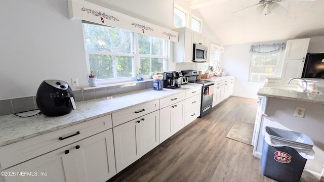 3822 County Road 220, Middleburg, FL 32068 - kitchen with range with electric cooktop, stainless steel microwave, wood finished floors, white cabinets, and light stone counters