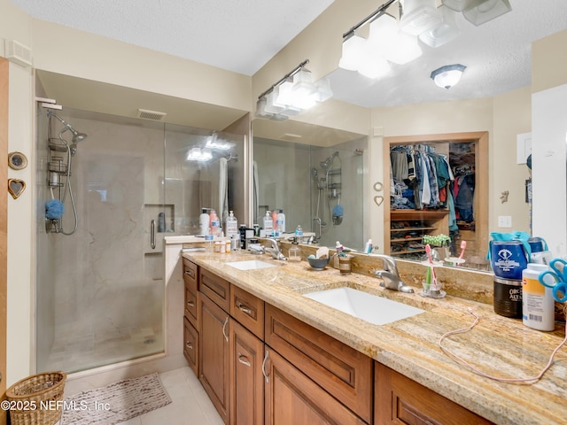 335 Sunrise Cir, Neptune Beach, FL 32266 - full bath featuring a stall shower, double vanity, a walk in closet, tile patterned floors, and a textured ceiling