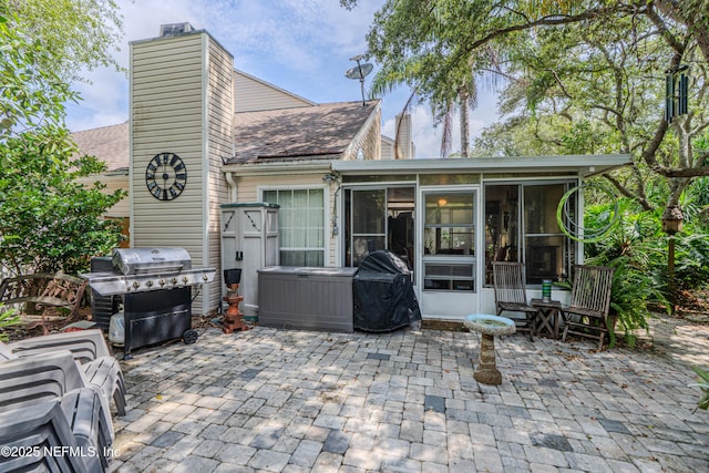335 Sunrise Cir, Neptune Beach, FL 32266 - rear view of property with a sunroom, a patio, a chimney, and roof with shingles