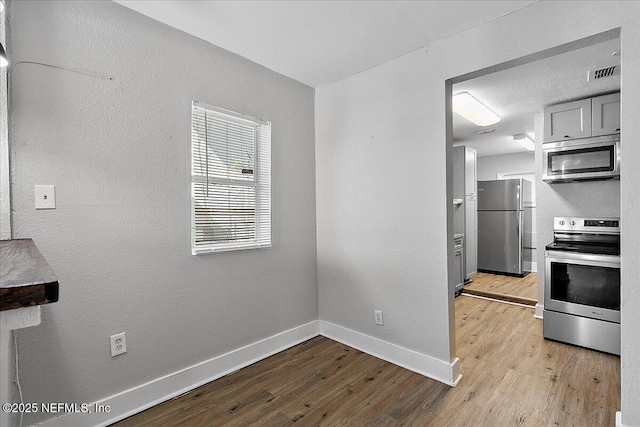 3607 Gilmore St, Jacksonville, FL 32205 - kitchen featuring stainless steel appliances, light wood-type flooring, gray cabinets, and a textured wall