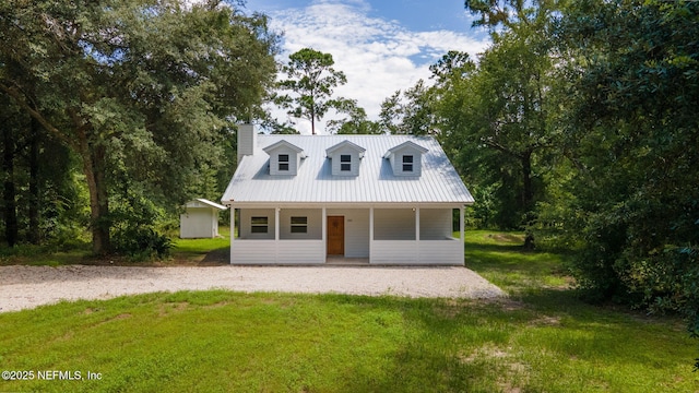 343 Tinsley Rd, Florahome, FL 32140 - cape cod house featuring a front lawn, a metal roof, a porch, a chimney, and an outbuilding