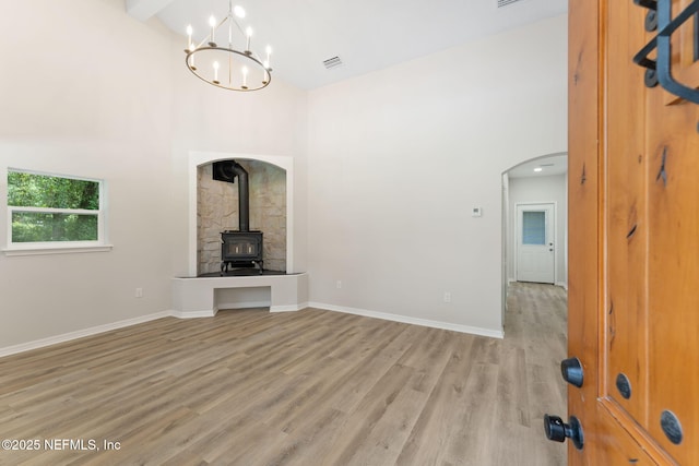 343 Tinsley Rd, Florahome, FL 32140 - unfurnished living room with high vaulted ceiling, a wood stove, light wood-type flooring, arched walkways, and a chandelier