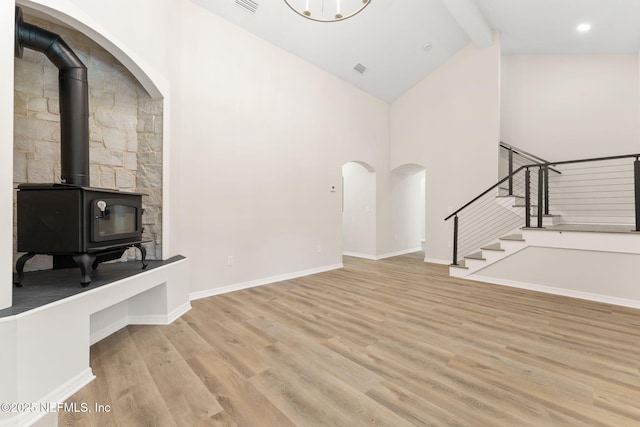 343 Tinsley Rd, Florahome, FL 32140 - unfurnished living room featuring stairs, wood finished floors, beamed ceiling, high vaulted ceiling, and a wood stove
