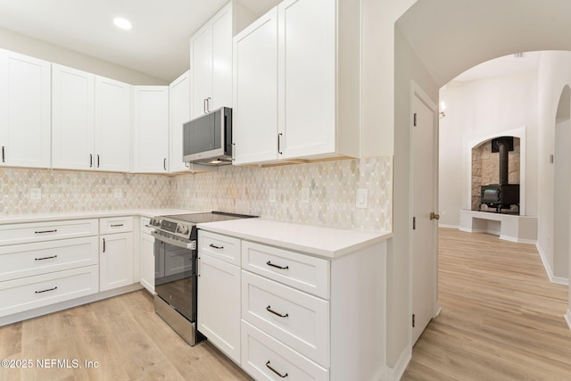 343 Tinsley Rd, Florahome, FL 32140 - kitchen featuring stainless steel appliances, light wood-style floors, a wood stove, arched walkways, and recessed lighting