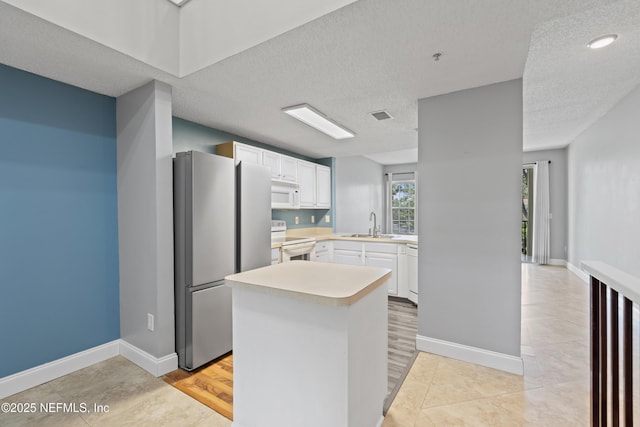 4000 Grande Vista Blvd Unit 15-106, Saint Augustine, FL 32084 - kitchen with white appliances, light countertops, white cabinets, a kitchen island, and a textured ceiling
