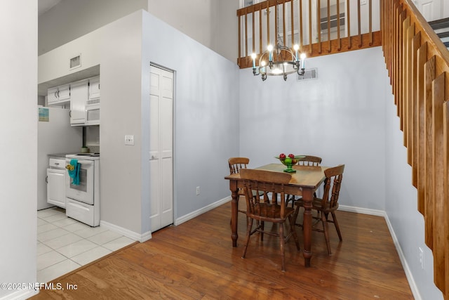 1430 Spindrift Cir E, Neptune Beach, FL 32266 - dining area featuring a chandelier, stairs, light wood-style floors, and a towering ceiling