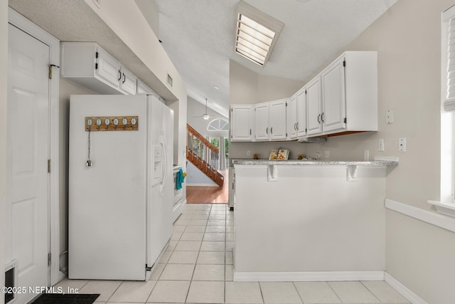 1430 Spindrift Cir E, Neptune Beach, FL 32266 - kitchen with white fridge with ice dispenser, white cabinets, light tile patterned floors, lofted ceiling, and a peninsula